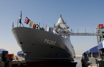 Leonardo signs huge naval combat systems deal for Kuwait Large gray naval vessel named P6202 docked at a pier, with signal flags along the bow and a gangway extending to shore.