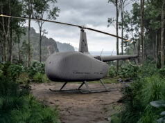 Grey autonomous helicopter drone with a two-bladed rotor on a forest path, rugged landing skids, surrounded by dense jungle.