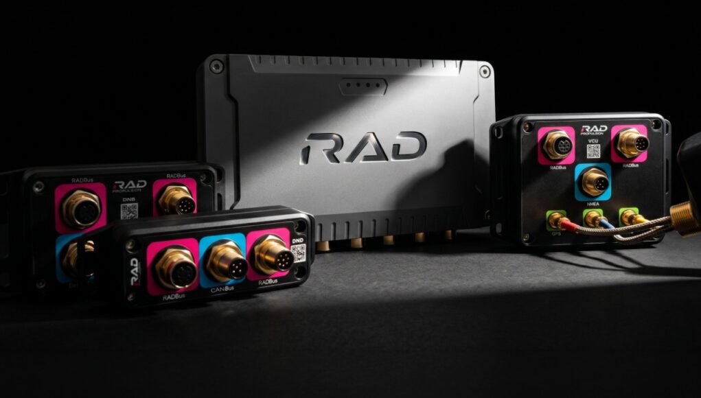 Black rugged avionics modules with gold round connectors and pink/blue label panels around a central RAD unit.