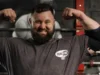 REME soldier first to reach England’s Strongest Man Bearded man in a gym flexing his biceps, wearing an Iron Rhino t-shirt, with weight racks in the background.