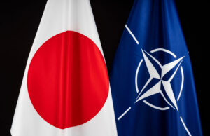 Japan sends personnel to NATO Ukraine support hub Two flags—Japan (white with red circle) and NATO (blue with white star-like emblem)—hung side by side against a dark background, symbolizing international cooperation.