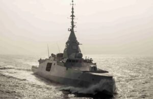 France orders fifth FDI frigate from Naval Group Surface warship sailing on calm sea with wake trailing behind, sun glare on the water.
