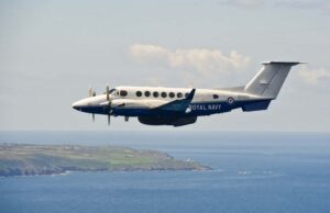 Second upgraded Avenger takes flight at Culdrose Twin-turboprop Royal Navy aircraft (ZZ503) in white and blue livery, flying low over the coastline and sea.