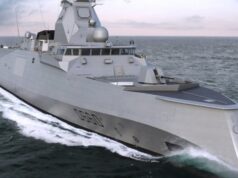Gray stealth destroyer sailing at sea, angular superstructure cutting through white water.