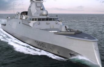Gray stealth destroyer sailing at sea, angular superstructure cutting through white water.