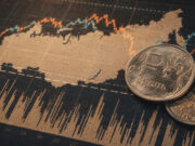 Russia sanctions at a crossroads as US commitment wavers Russian ruble coins placed on a stock market chart showing fluctuating lines and data.
