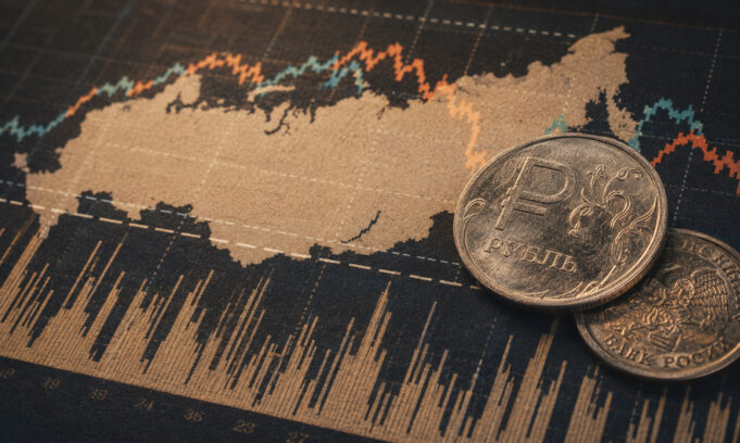 Russian ruble coins placed on a stock market chart showing fluctuating lines and data.