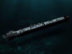 Torpedo submerged in dark ocean water, trailing bubbles as it drifts forward.
