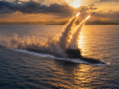 Submarine at sea firing two missiles during sunset, large smoke plumes rising into the sky over calm water.