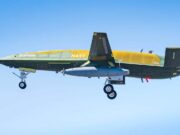 Military aircraft in flight with landing gear down against a clear blue sky, labeled NAVY on its fuselage.