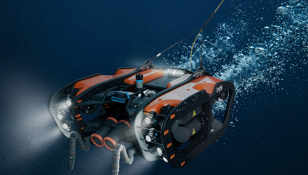 syos-su10-uuv Underwater orange-and-black submersible drone with lights cruising through deep blue water.