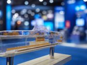 Transparent submarine model on a pedestal, showing orange internal components at a blue-lit expo hall display center.