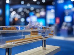 Transparent submarine model on a pedestal, showing orange internal components at a blue-lit expo hall display center.