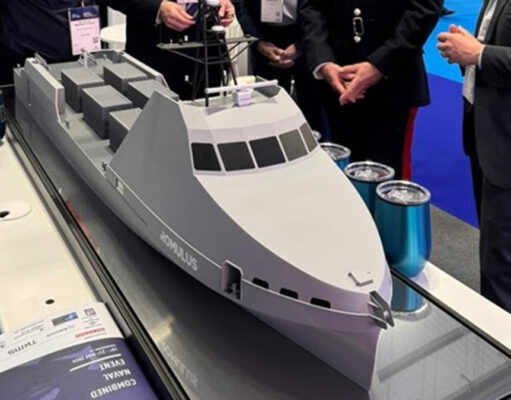 HII showcases REMUS and ROMULUS at CNE Scale model cruise ship on a display table at an exhibition, with people in business attire gathered around.