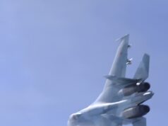 Russian jet dangerously close to British military aircraft Blurred fighter jet ascending into a clear blue sky, twin vertical tails visible at the rear.