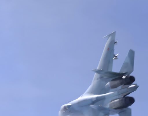 Russian jet dangerously close to British military aircraft Blurred fighter jet ascending into a clear blue sky, twin vertical tails visible at the rear.