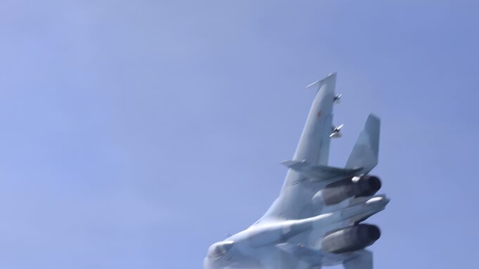 Russian jet dangerously close to British military aircraft Blurred fighter jet ascending into a clear blue sky, twin vertical tails visible at the rear.