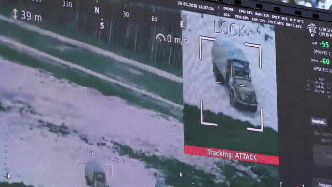Surveillance display highlighting a truck on a road, with a crosshair overlay and a red 'Tracking ATTACK' label below the image.