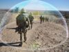 First prototypes of troop-protection jammer due in 2027 Soldiers in camouflage marching along a rocky desert path beside a barbed-wire fence, with a translucent arc overlayed across the scene.