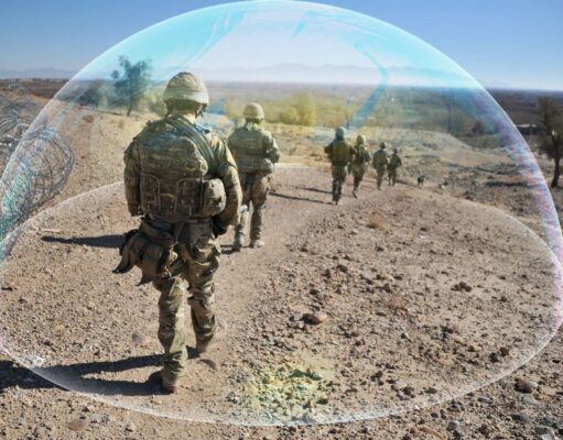 Soldiers in camouflage marching along a rocky desert path beside a barbed-wire fence, with a translucent arc overlayed across the scene.