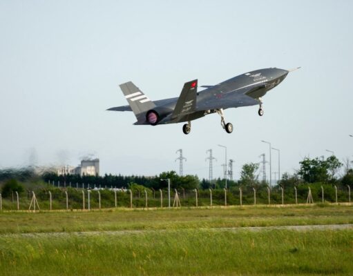 Italian jets fly with Turkish drones in K-SWARM live trial Stealth fighter jet lifting off from a runway, low above a grassy field with a fence in the foreground.