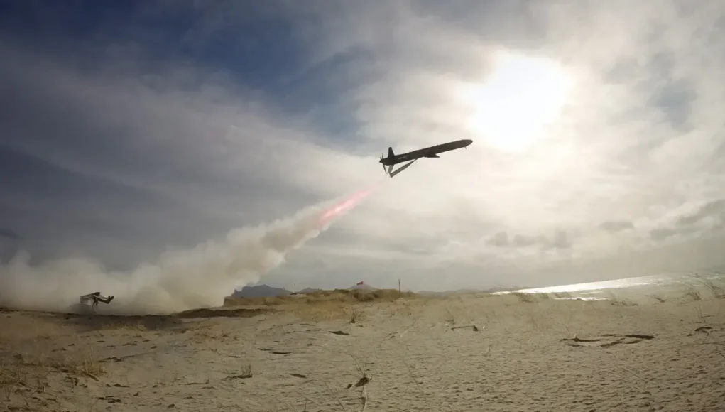 6a02fa6469a9514cf1ba5609_skylance-launch-banner-p-1600 Air tanker plane releasing red retardant over a sandy beach as smoke rises from a ground fire nearby