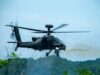 American Apaches fire rockets near the Korean DMZ Military attack helicopter in mid-flight firing a missile over a forested area