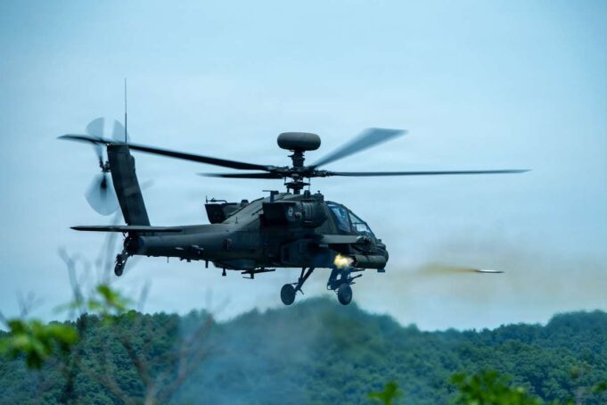 American Apaches fire rockets near the Korean DMZ Military attack helicopter in mid-flight firing a missile over a forested area