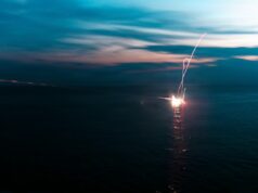 American Marines open fire in the South China Sea Firework explosion on the water at dusk, long-exposure light trail over the dark sea.