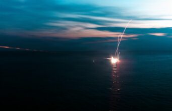 American Marines open fire in the South China Sea Firework explosion on the water at dusk, long-exposure light trail over the dark sea.