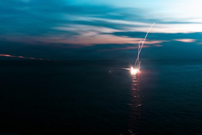 American Marines open fire in the South China Sea Firework explosion on the water at dusk, long-exposure light trail over the dark sea.