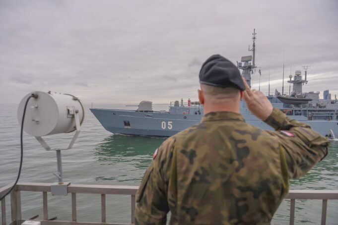 NATO kicks off huge BALTOPS drill to deter Russia Sailor in camouflage uniform saluting as a gray warship with the number 05 passes by on the water.