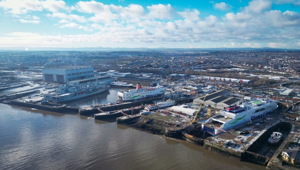 Balaena Birkenhead Aerial view of a harbor with two large white Stena Line ferries docked at the quay and industrial buildings nearby under a blue, cloudy sky.