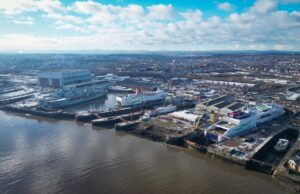 Aerial view of a harbor with two large white Stena Line ferries docked at the quay and industrial buildings nearby under a blue, cloudy sky.