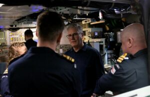 Starmer tells NATO chief UK will publish DIP before summit An older man with glasses speaks to a group of uniformed sailors inside a technical control room or ship compartment.