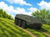 Six-wheeled armored military vehicle climbs a dirt path through a grassy hillside under a bright blue sky with clouds.