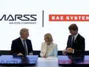 MARSS picked to run command brain of BAE drone-killer Three businesspeople in suits signing documents at a table, with MASS and BAE SYSTEMS logos in the bright backdrop.