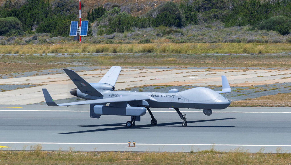 PROTECTORPOD Unmanned RAF surveillance aircraft on a runway, with two large wings and a light gray fuselage marked 'ROYAL AIR FORCE'.