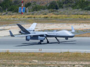 British drone spotted carrying covert spy pod Unmanned RAF surveillance aircraft on a runway, with two large wings and a light gray fuselage marked 'ROYAL AIR FORCE'.