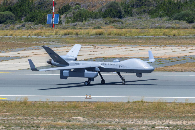 British drone spotted carrying covert spy pod Unmanned RAF surveillance aircraft on a runway, with two large wings and a light gray fuselage marked 'ROYAL AIR FORCE'.