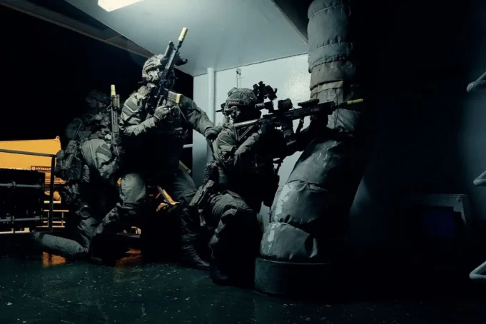 3 Commando Brigade renamed the UK Commando Force Special forces operators in full tactical gear crouch and aim rifles in a dim corridor of a vessel or building.