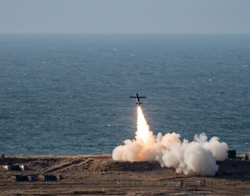 Small airplane launches a rocket from a coastal test site, flame and smoke plume rising toward the sky over the ocean.