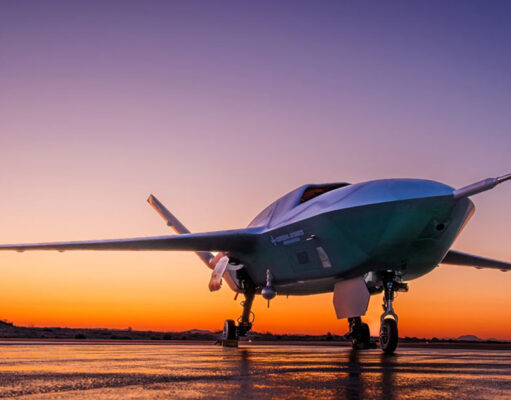 US Air Force orders uncrewed fighter into production Low-angle shot of a futuristic green aircraft parked on a wet runway at sunset, orange sky behind.