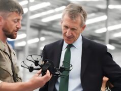 New Defence Secretary opens huge drone centre in Swindon Military personnel in camouflage hands a tactical vest to a businessman in a suit inside a hangar, as they converse.
