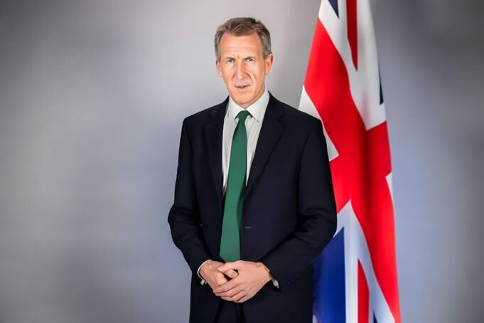 Who is Dan Jarvis? A look at Britain’s new defence secretary Portrait of a man in a dark suit and green tie standing beside a Union Jack flag behind him. (informative)