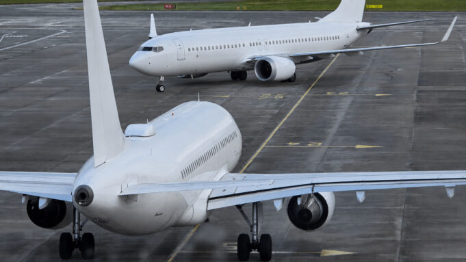 Number of UK airports hit by aviation fuel supply issue Two large white commercial aircraft on an airport tarmac, one in the foreground viewed from the rear with engines and tail visible, another taxiing in the background.