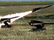 US clears large Hawk sustainment package for Ukraine Two missiles launch from mobile ground launchers in a grassy field, producing bright flames and smoke trails.