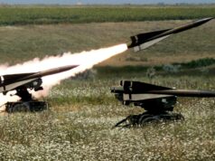 US clears large Hawk sustainment package for Ukraine Two missiles launch from mobile ground launchers in a grassy field, producing bright flames and smoke trails.
