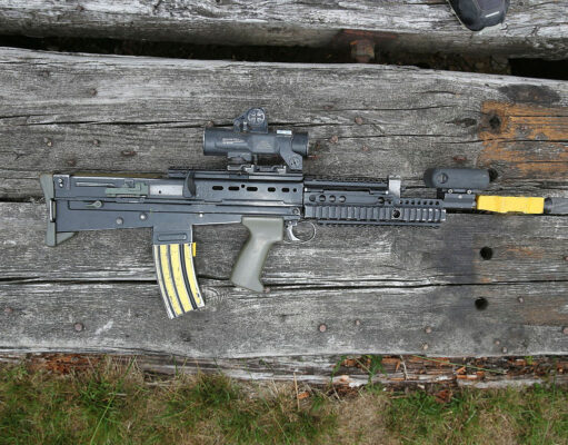 Up to two billion pounds to replace the SA80 rifle Assault rifle with scope and foregrip lying on weathered wooden planks.