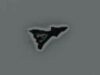 Small black irregular triangular sticker with a white outline on a gray surface, facing to the right.